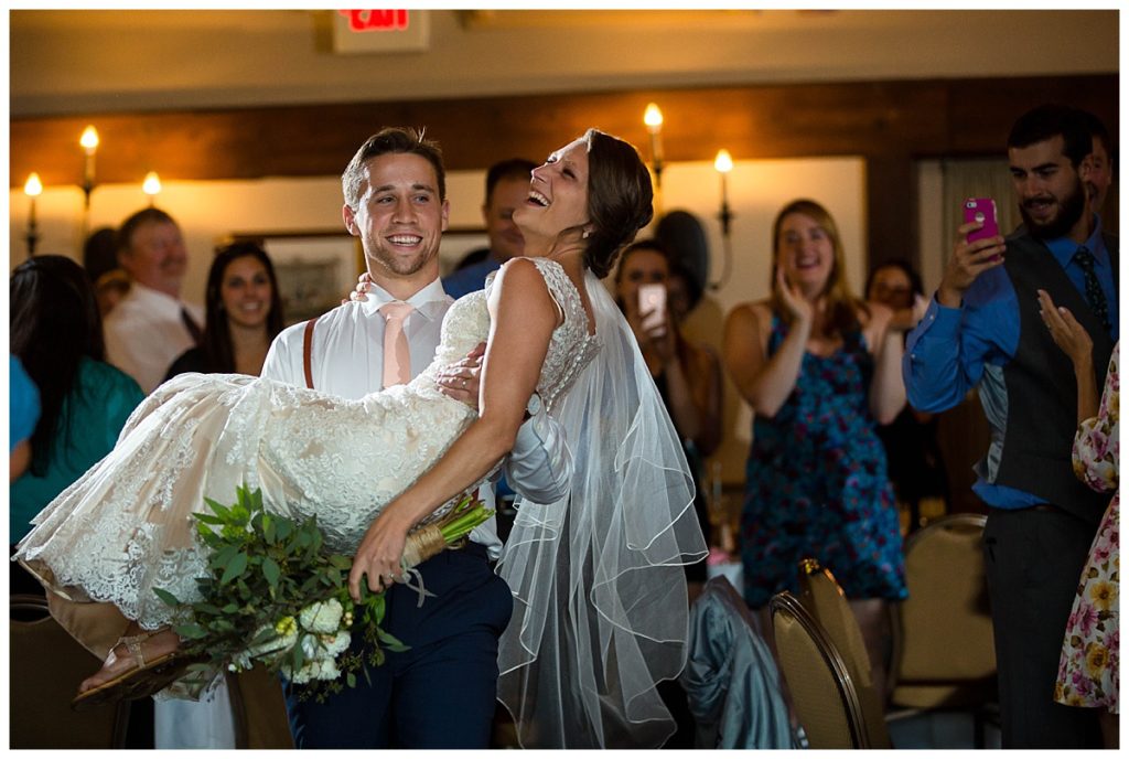 groom carrying bride into reception at the Publick House
