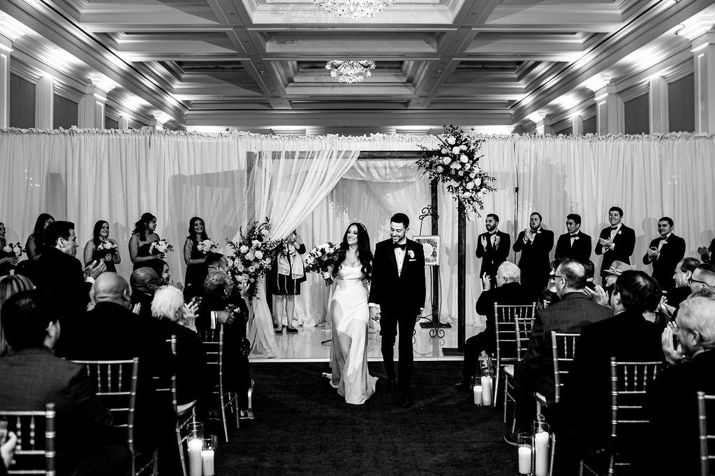 A bride and groom walk down the aisle at Ballroom at Ellis Preserve