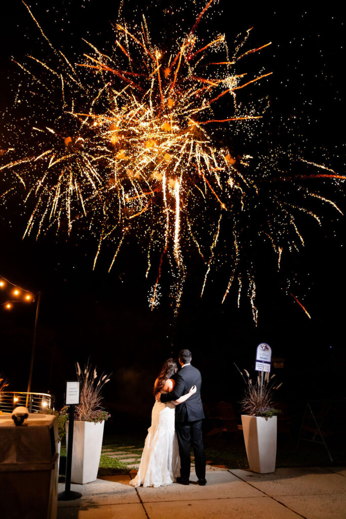 A bride and groom watch fireworks. 