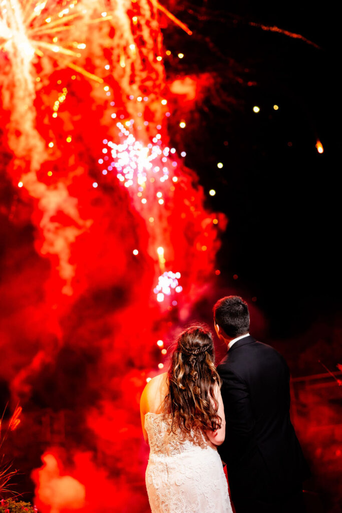 A bride and groom take in fireworks on their wedding day. 