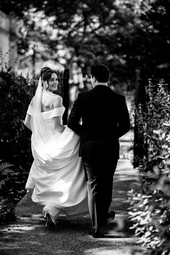 A bride walks while holding her dress. 